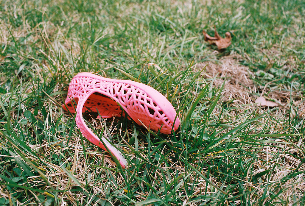 A child’s size 2 pink shoe tossed aside in grass